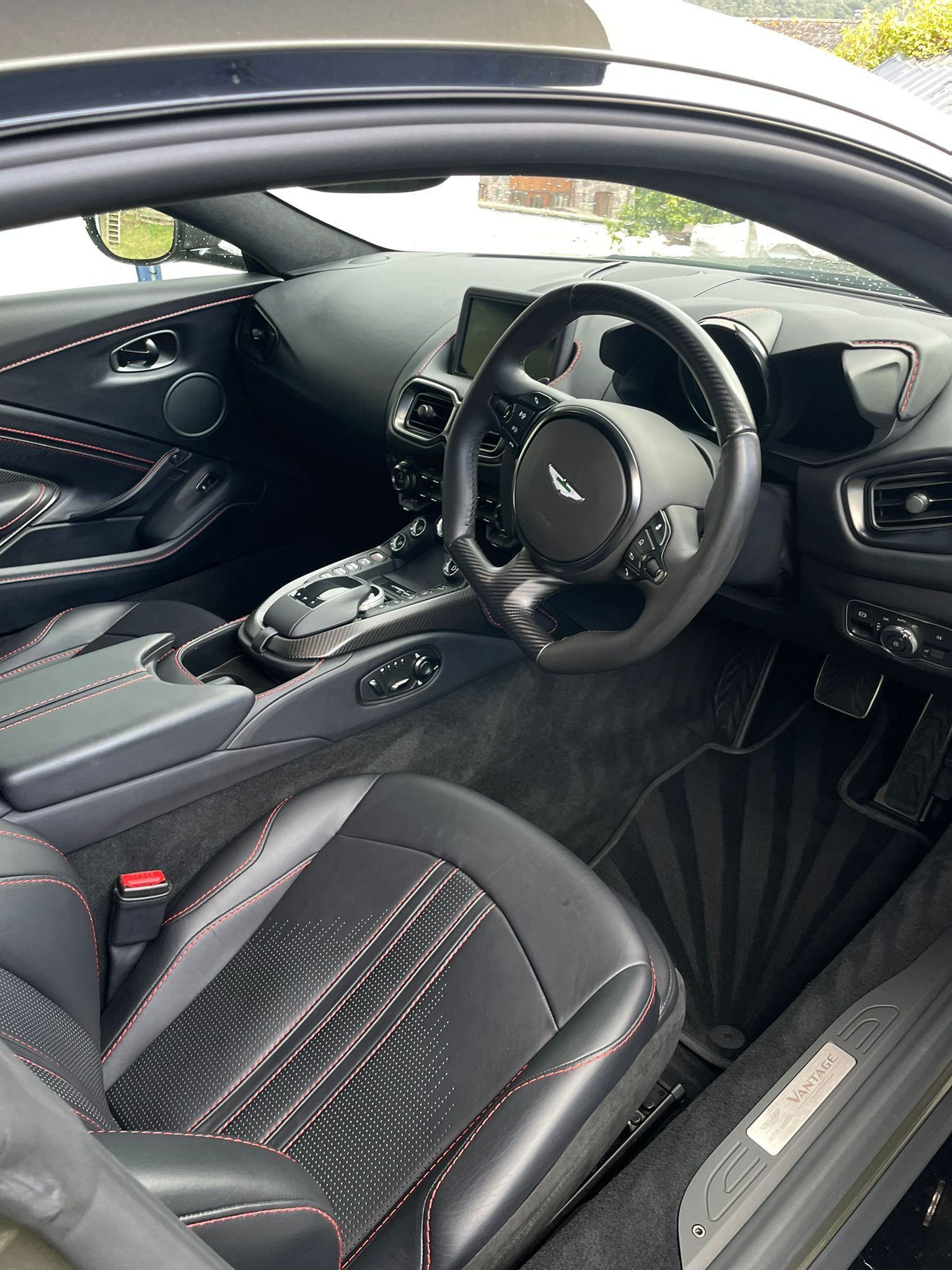 Black Aston Martin interior with red stitching accents.