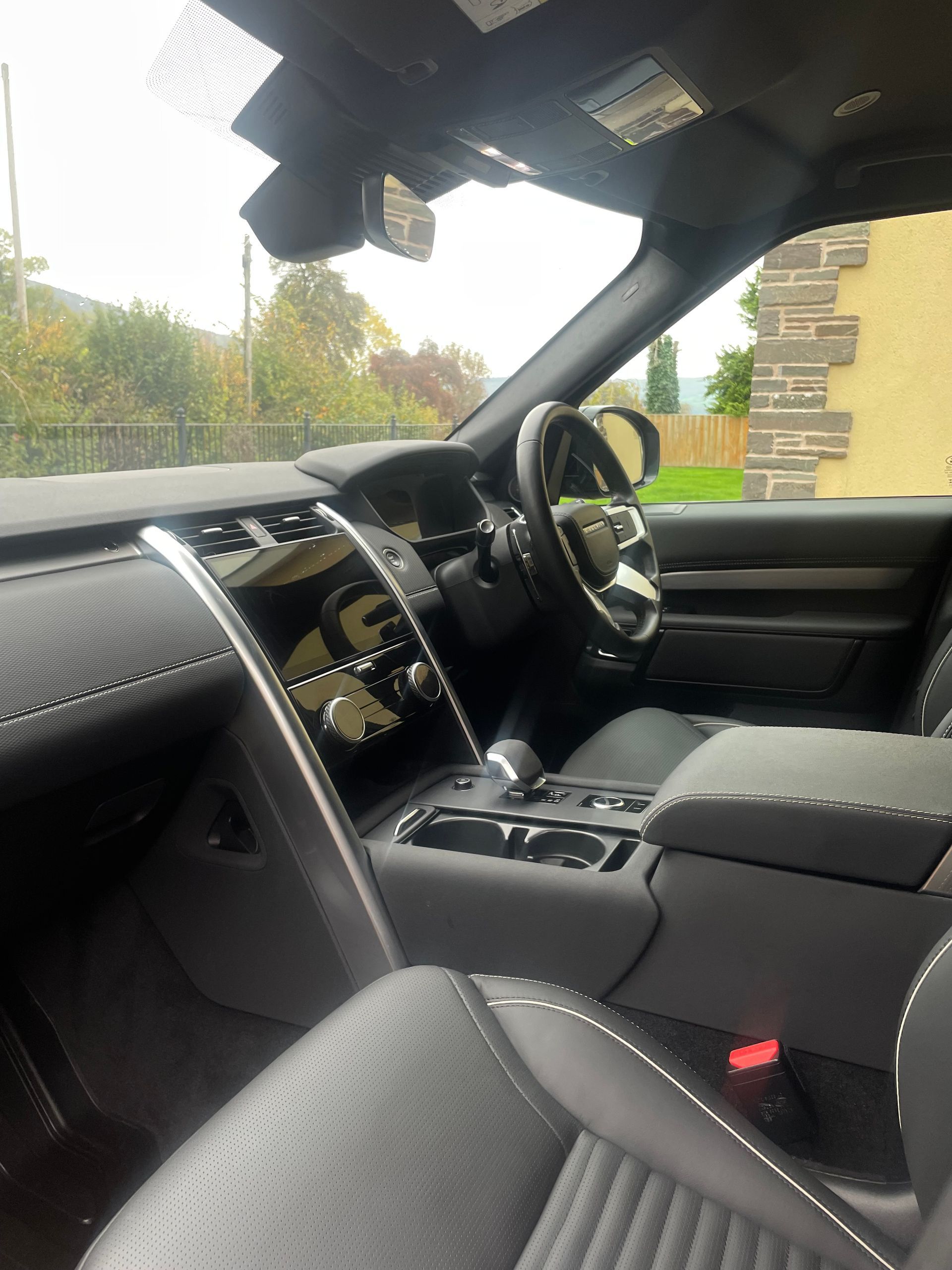 Interior view of a Land Rover vehicle with a dark leather dashboard, steering wheel, and perforated leather seats.