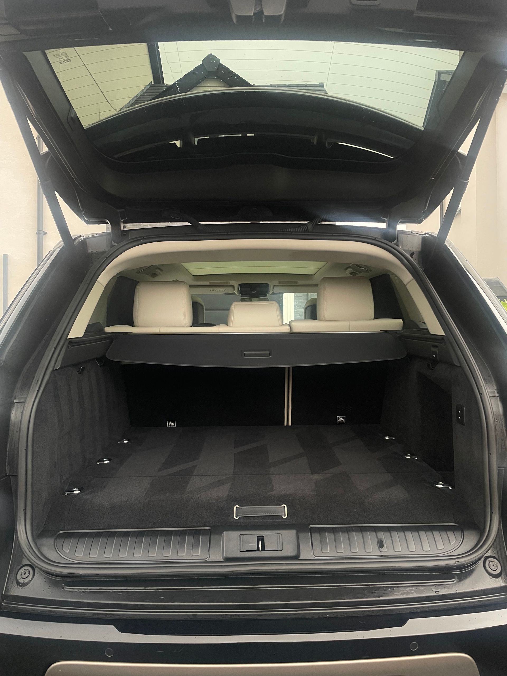 An open trunk of a black SUV revealing a clean, carpeted cargo area and the back of cream-colored passenger seats.