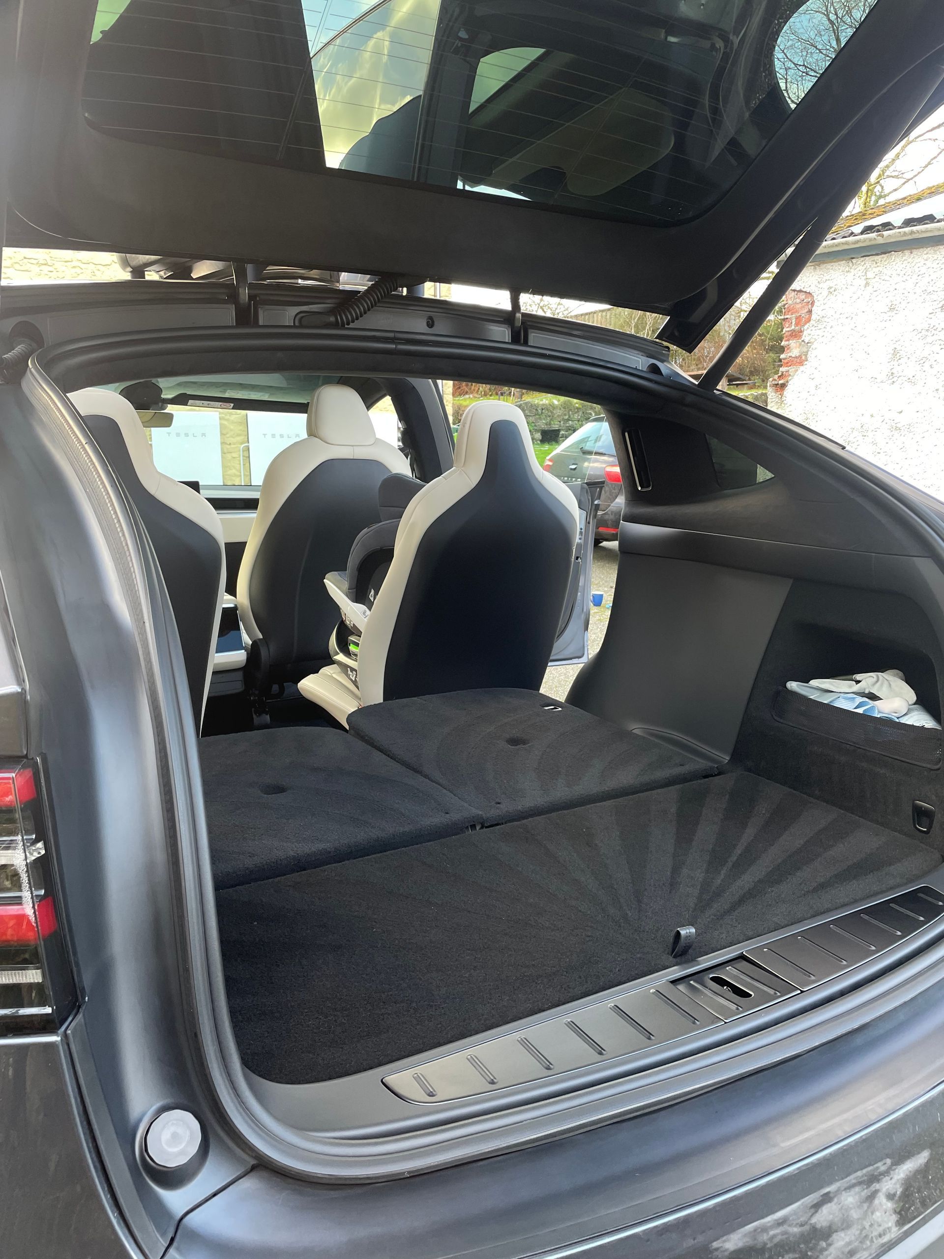 A view inside the open trunk of an SUV with the back seats folded down to create a flat, black carpeted cargo area.