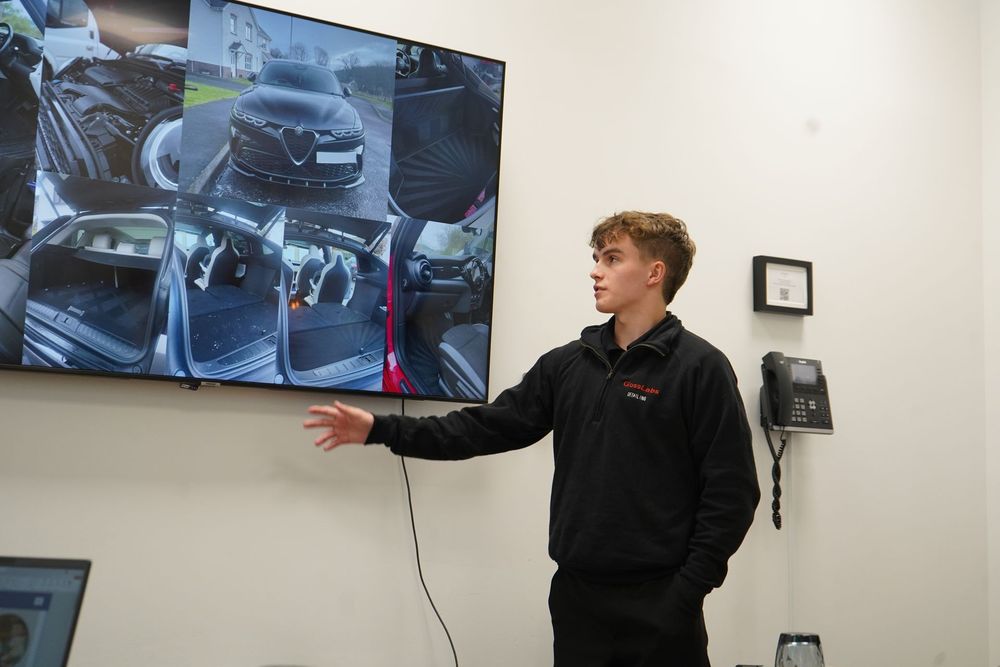 Man washing a car tire with a brush, white foam, outdoors.