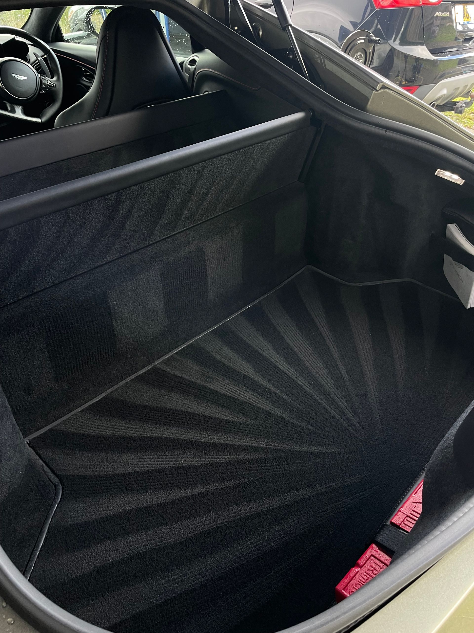 The clean, black-carpeted cargo area of a car, featuring a distinct, radiating sunburst pattern vacuumed into the mat.