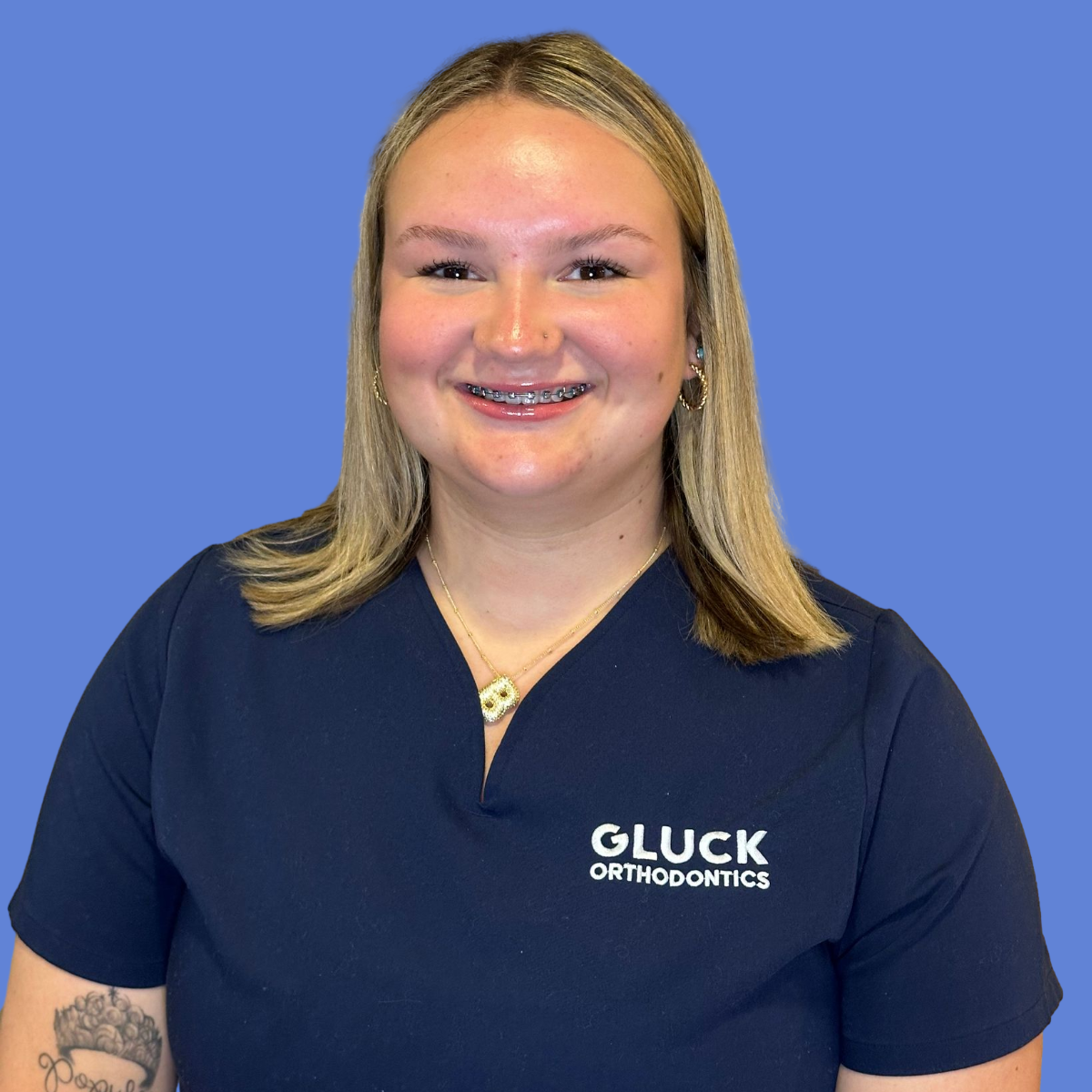 A woman in a black scrub top is smiling in a circle.