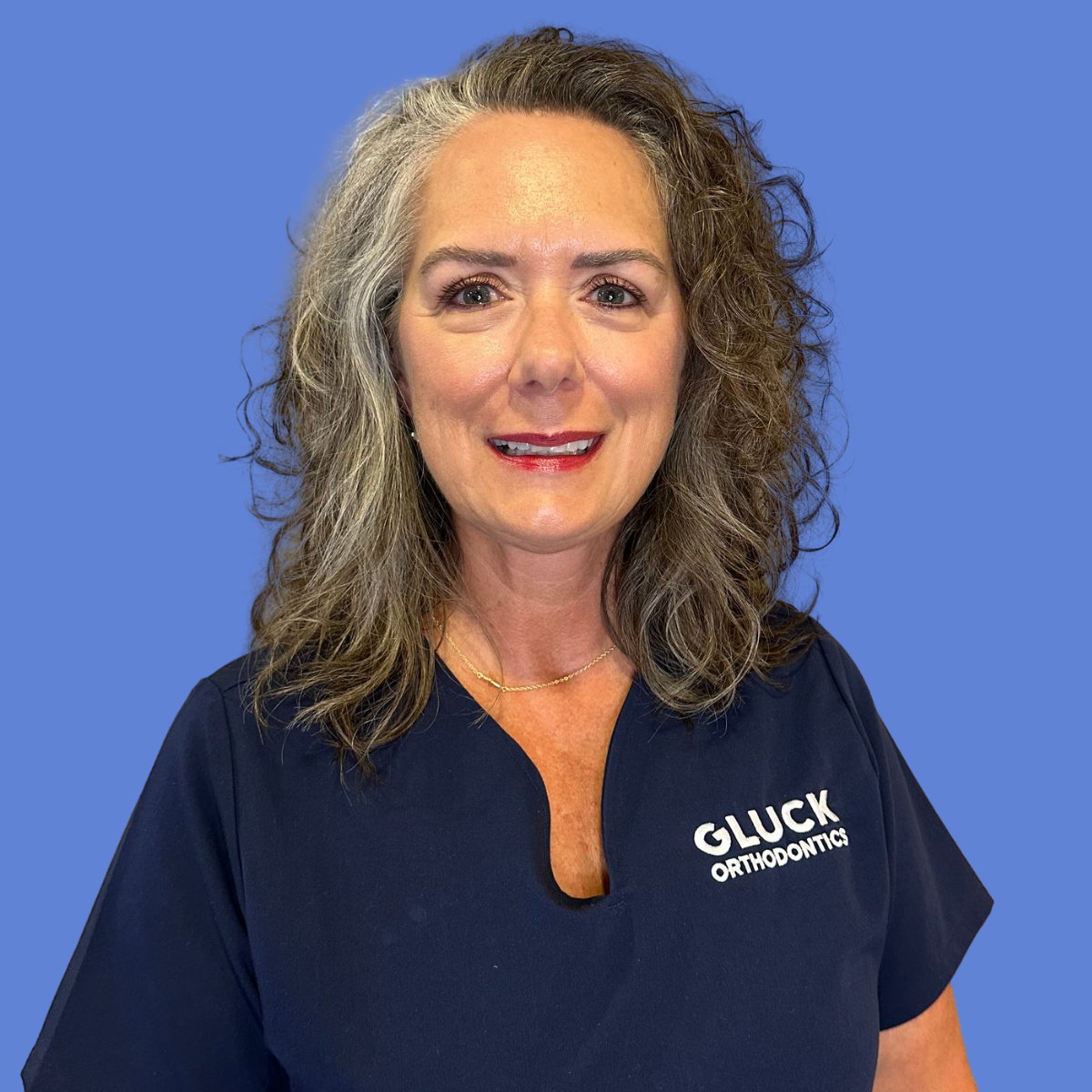 A woman in a black scrub top is smiling in a circle.