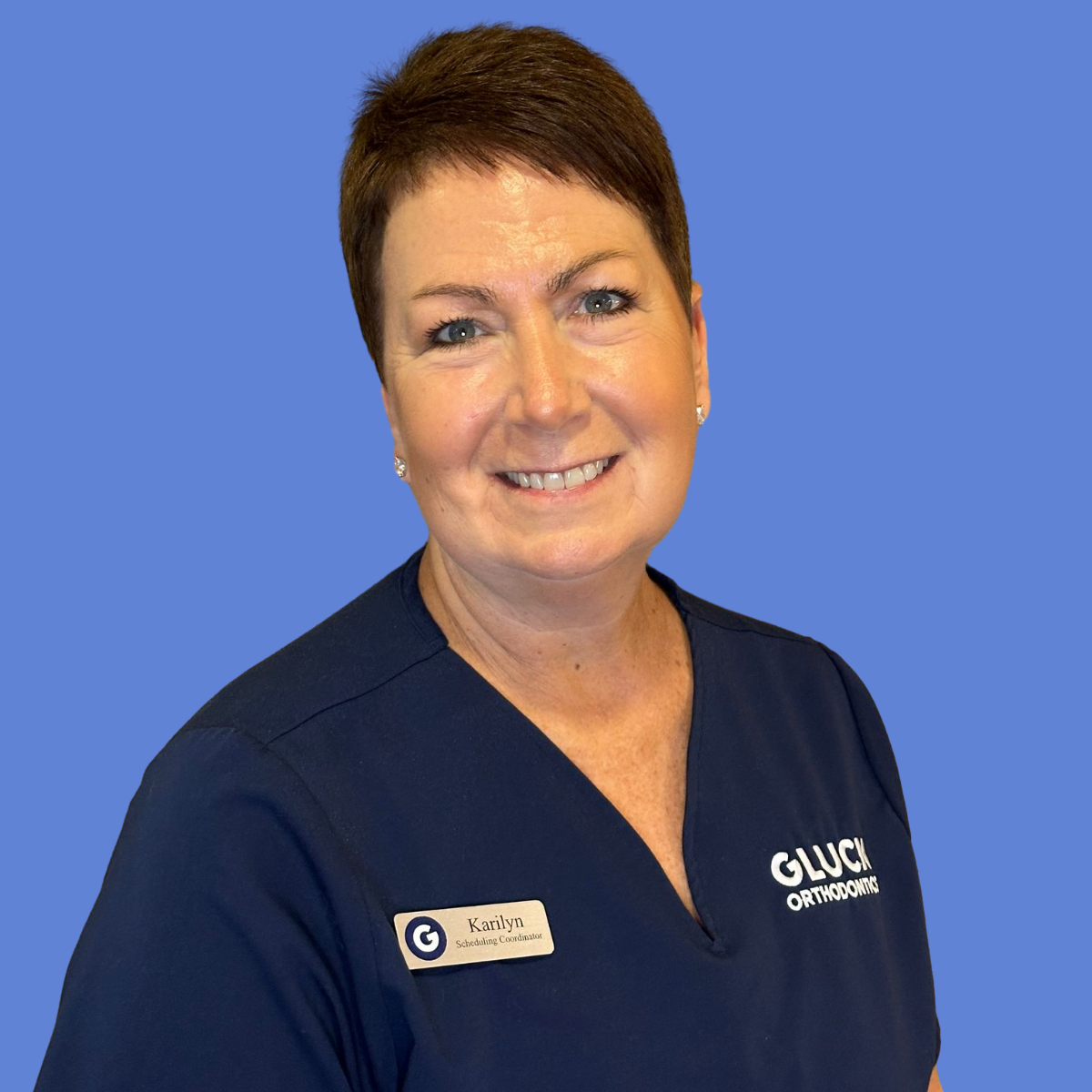 A woman wearing a black scrub top with the name karlyn on it