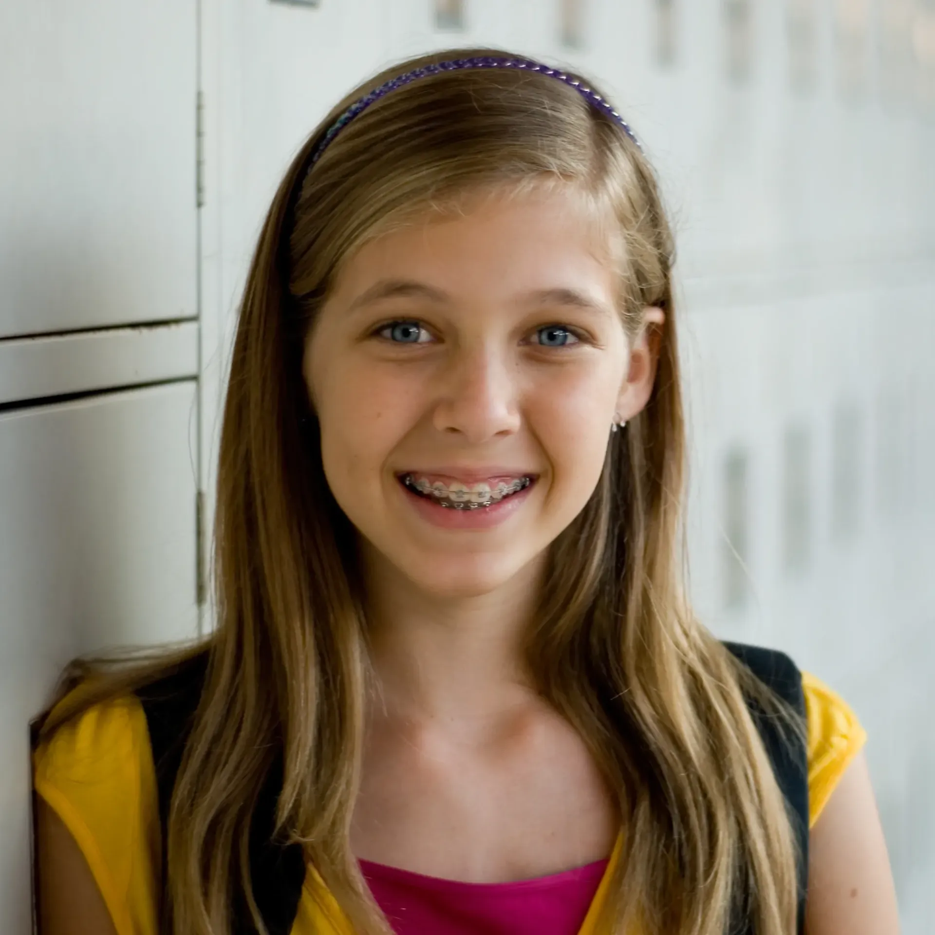 A young girl with braces on her teeth smiles for the camera