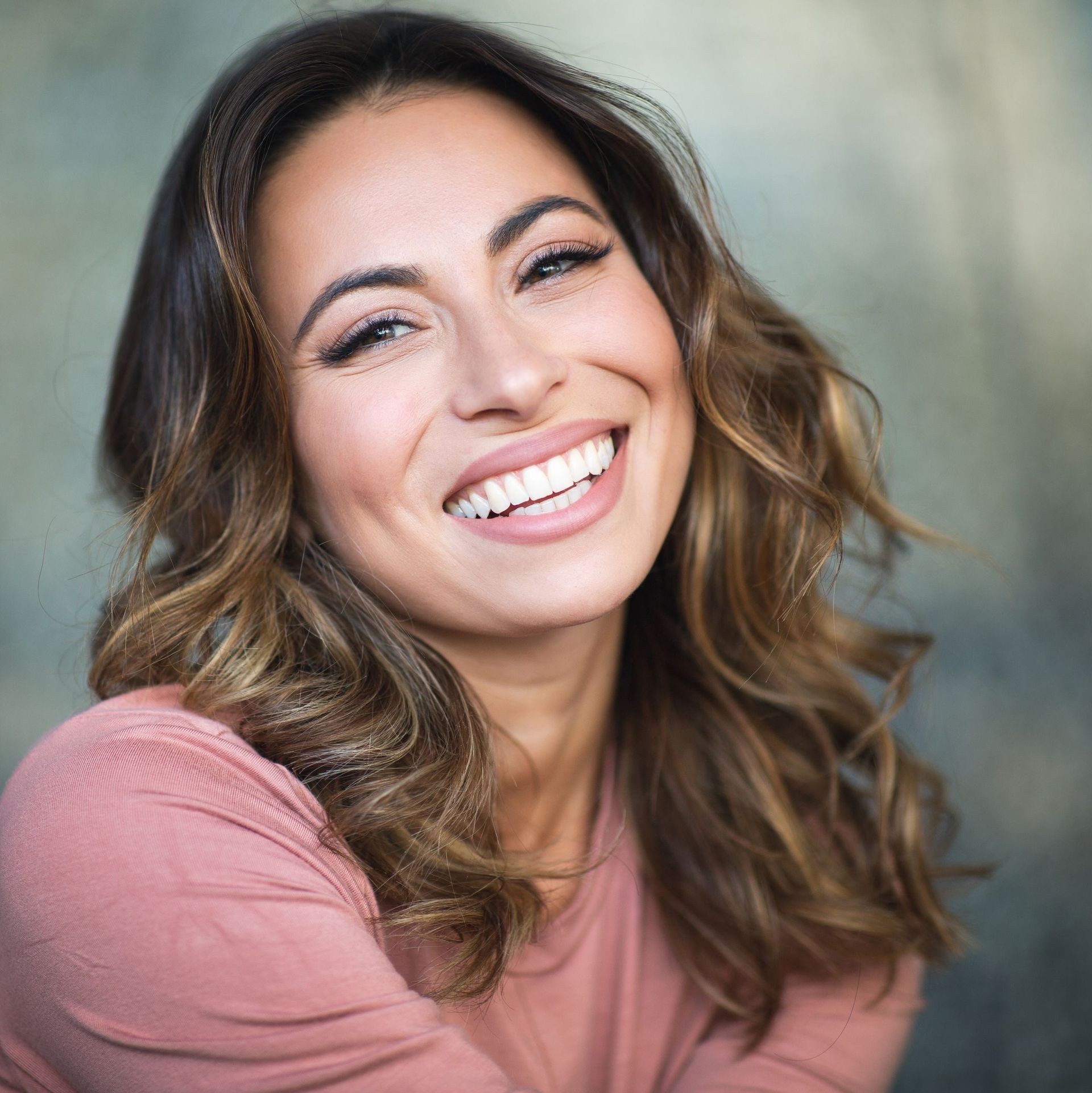 A woman in a pink shirt is smiling for the camera