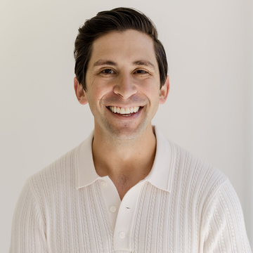 Smiling man in a white sweater against a light background