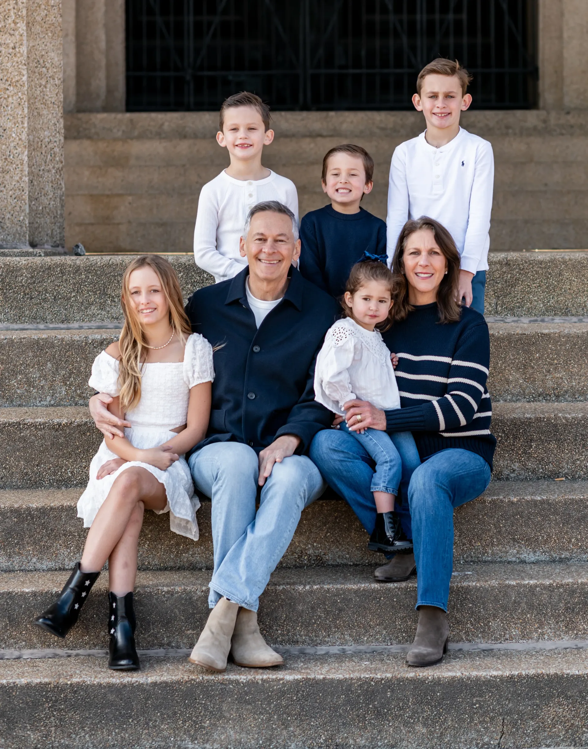 A family is posing for a picture on the steps of a building.