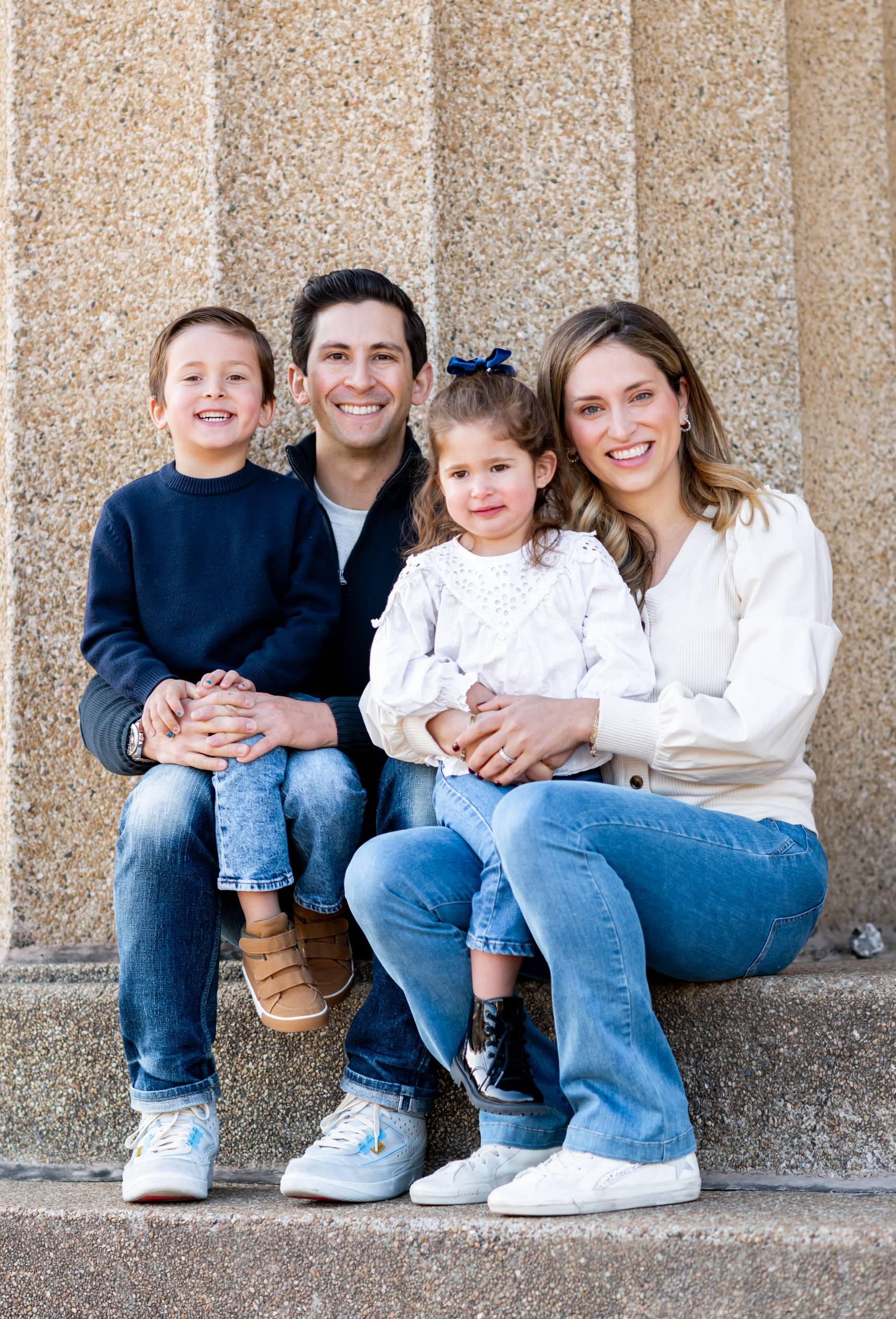 A family is sitting on the steps of a building.