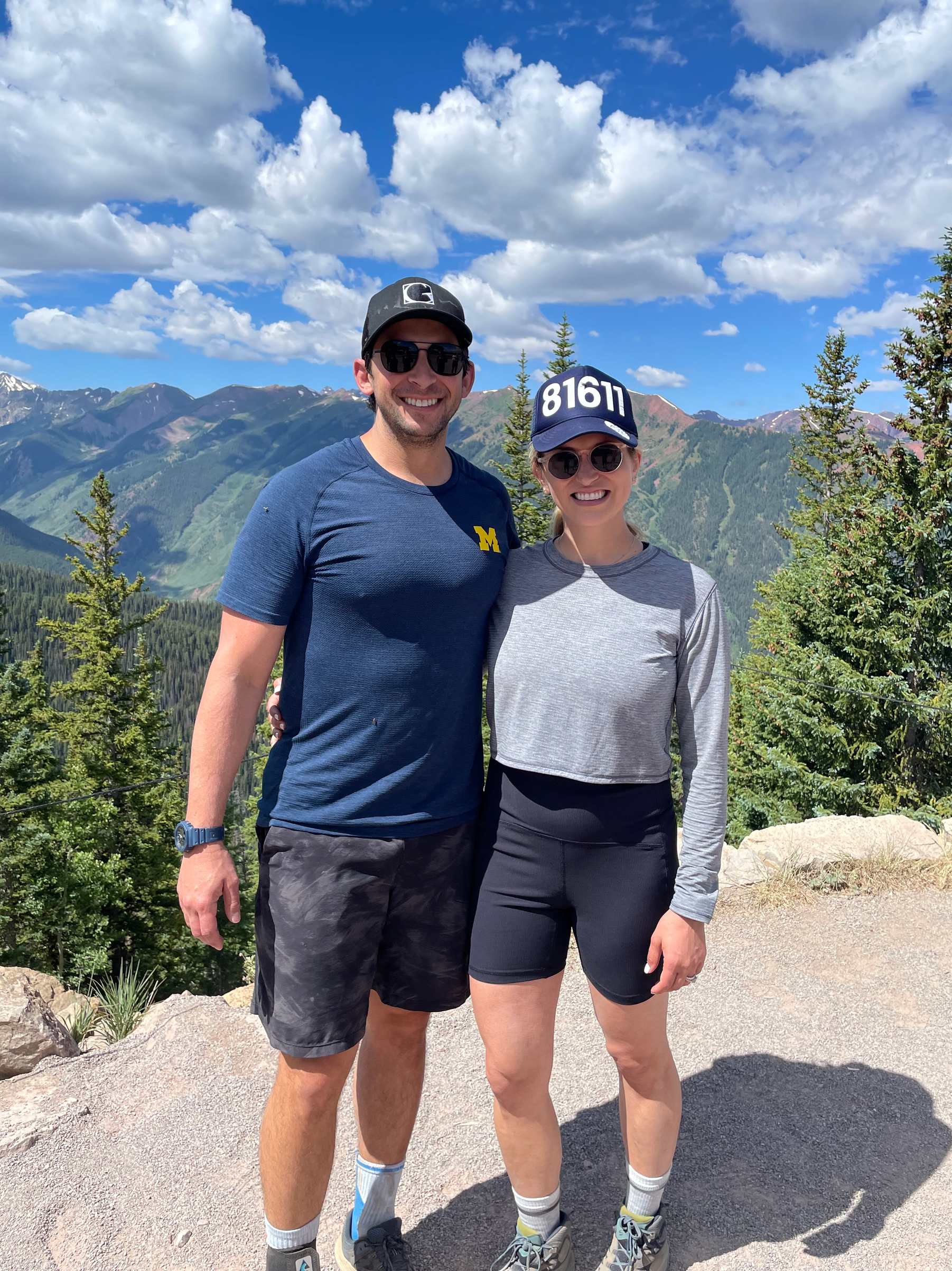 A man and a woman are posing for a picture on top of a mountain.