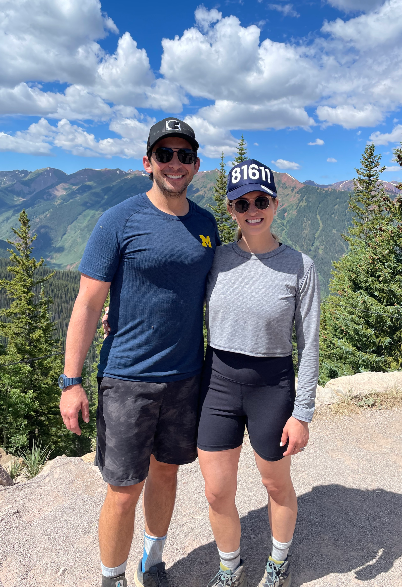 A man and a woman are posing for a picture on top of a mountain.