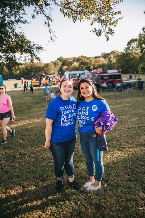 Two women are standing next to each other in a field.