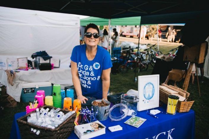 A woman in a blue shirt is standing in front of a table.