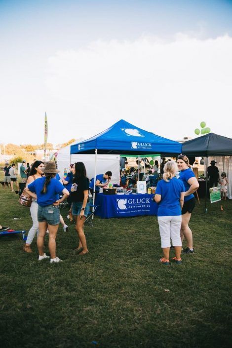 A group of people are standing in a field in front of a blue tent.