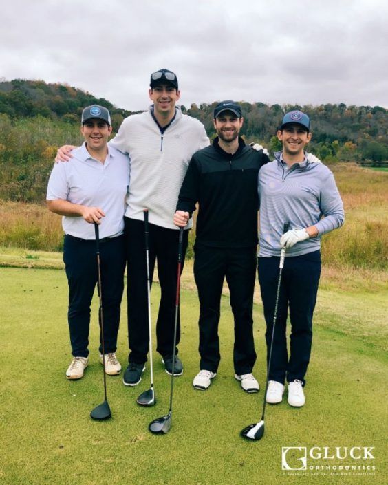 Four men are posing for a picture on a golf course
