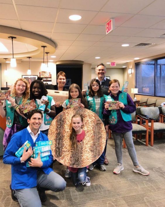 A group of girl scouts pose for a picture in a waiting room