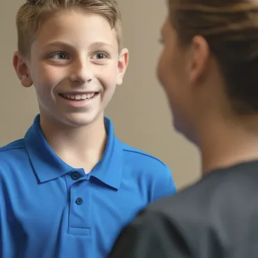 A boy in a blue shirt is smiling while talking to a woman in black scrubs