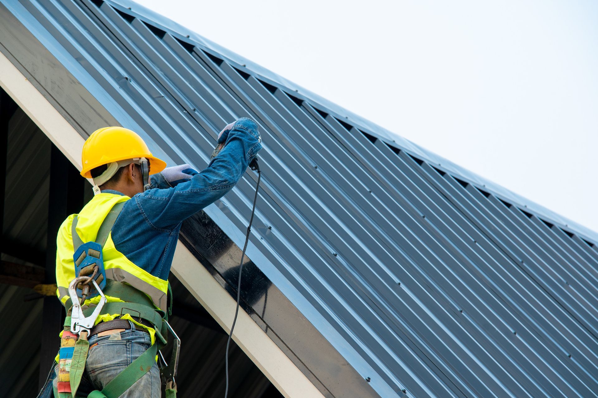Construction worker wearing safety harness are working install new roof.