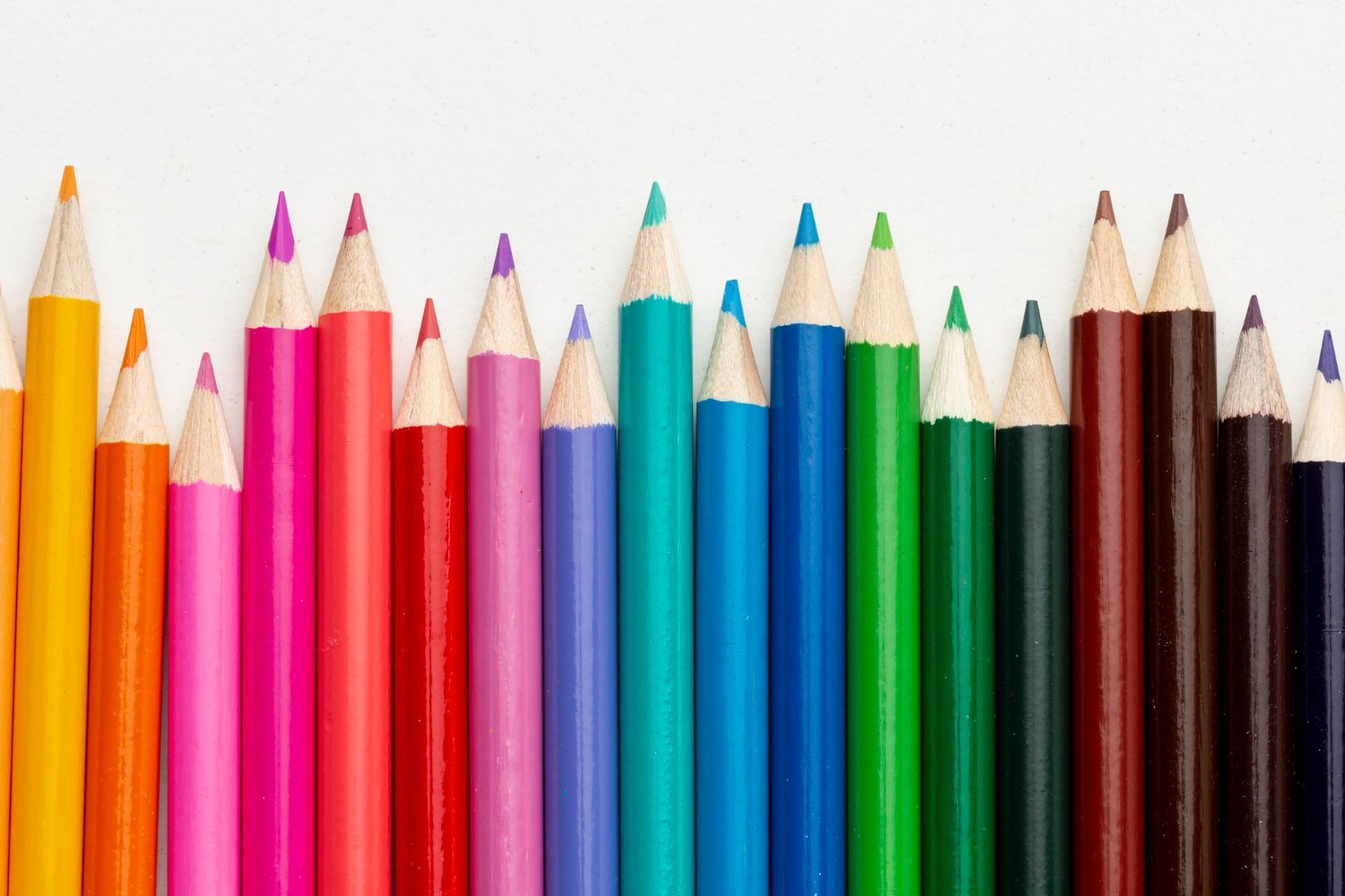 Row of colorful sharpened pencils on a white background, arranged by color.