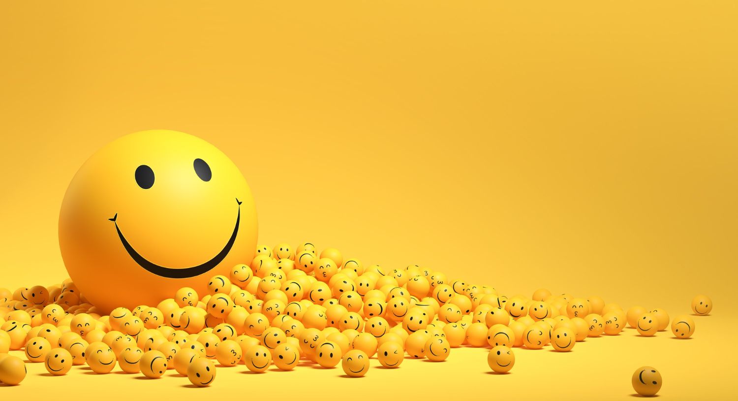 Large yellow smiley face ball surrounded by many smaller smiley face balls on a yellow background.
