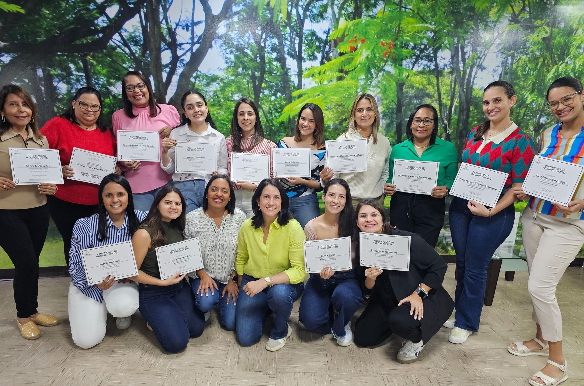 Group of women holding signs, posing in front of a forest mural.