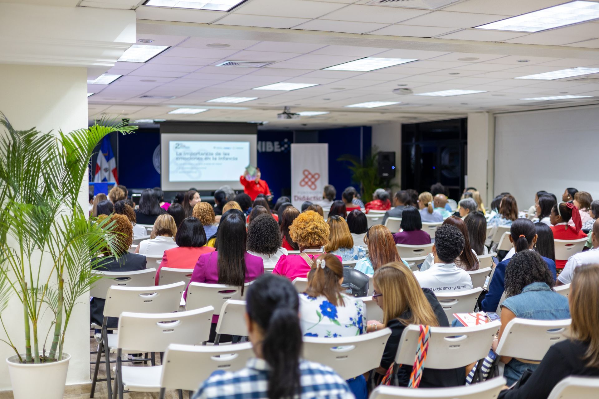 Audience in a conference room listening to a presentation on a screen.