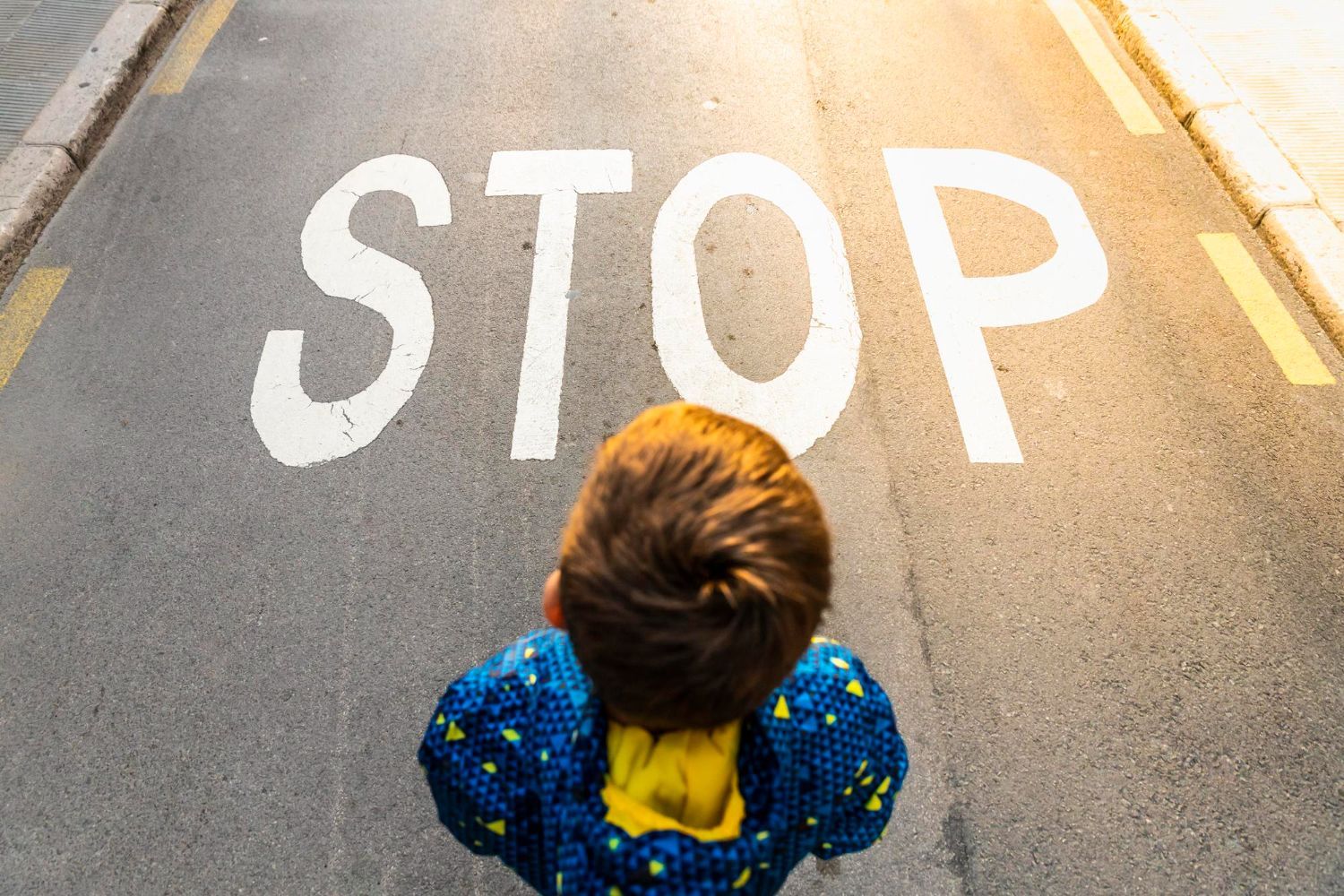 A child in a blue jacket stands before a large 