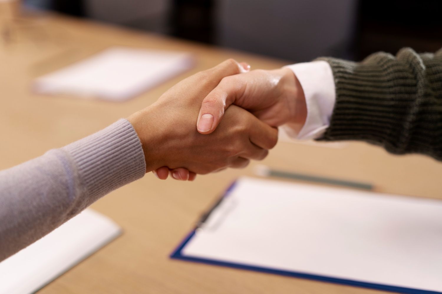 Hands shaking over a clipboard, signifying agreement or a deal.