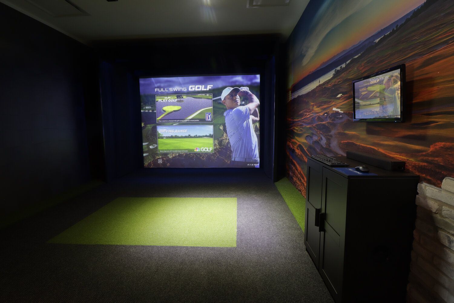 A man is playing golf in a simulator in a dark room.