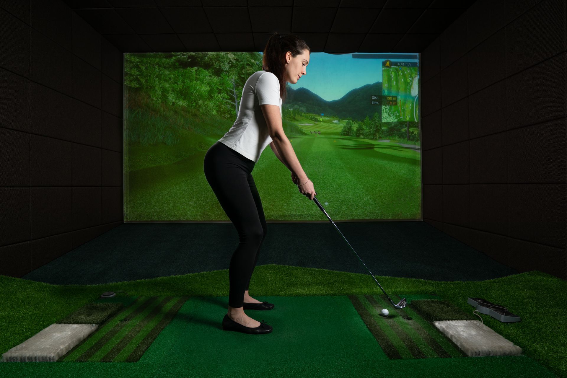A woman is playing golf in a simulator.