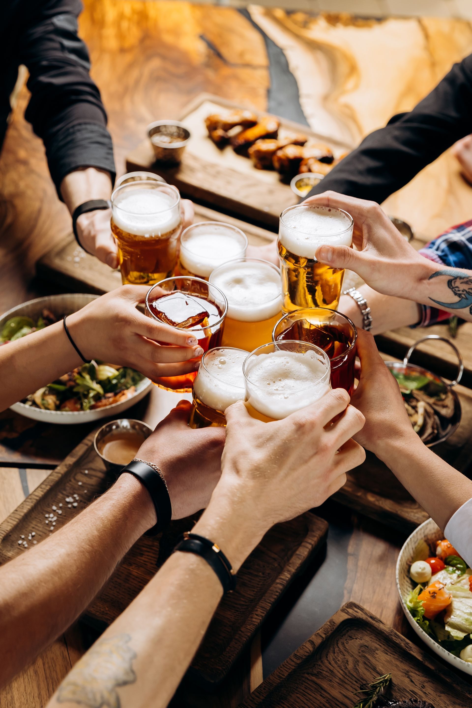A group of people are toasting with beer at a table.