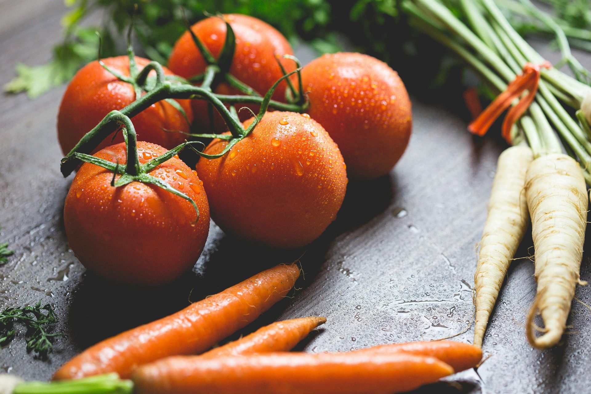 Tomatoes and carrots are sitting on a wooden table.