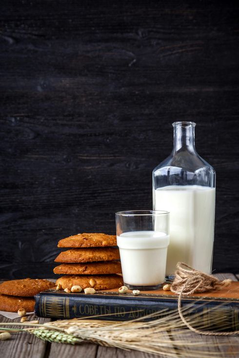 There is a bottle of milk and a glass of milk on the table.