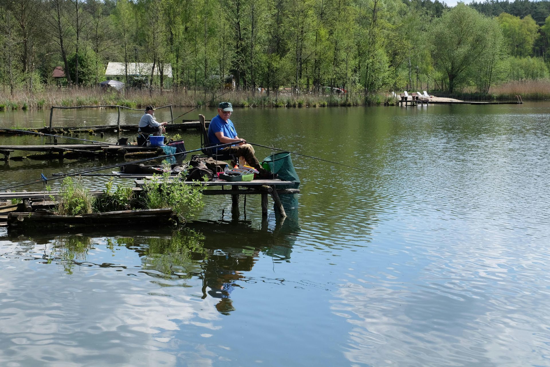 A man is sitting on a dock fishing in a lake