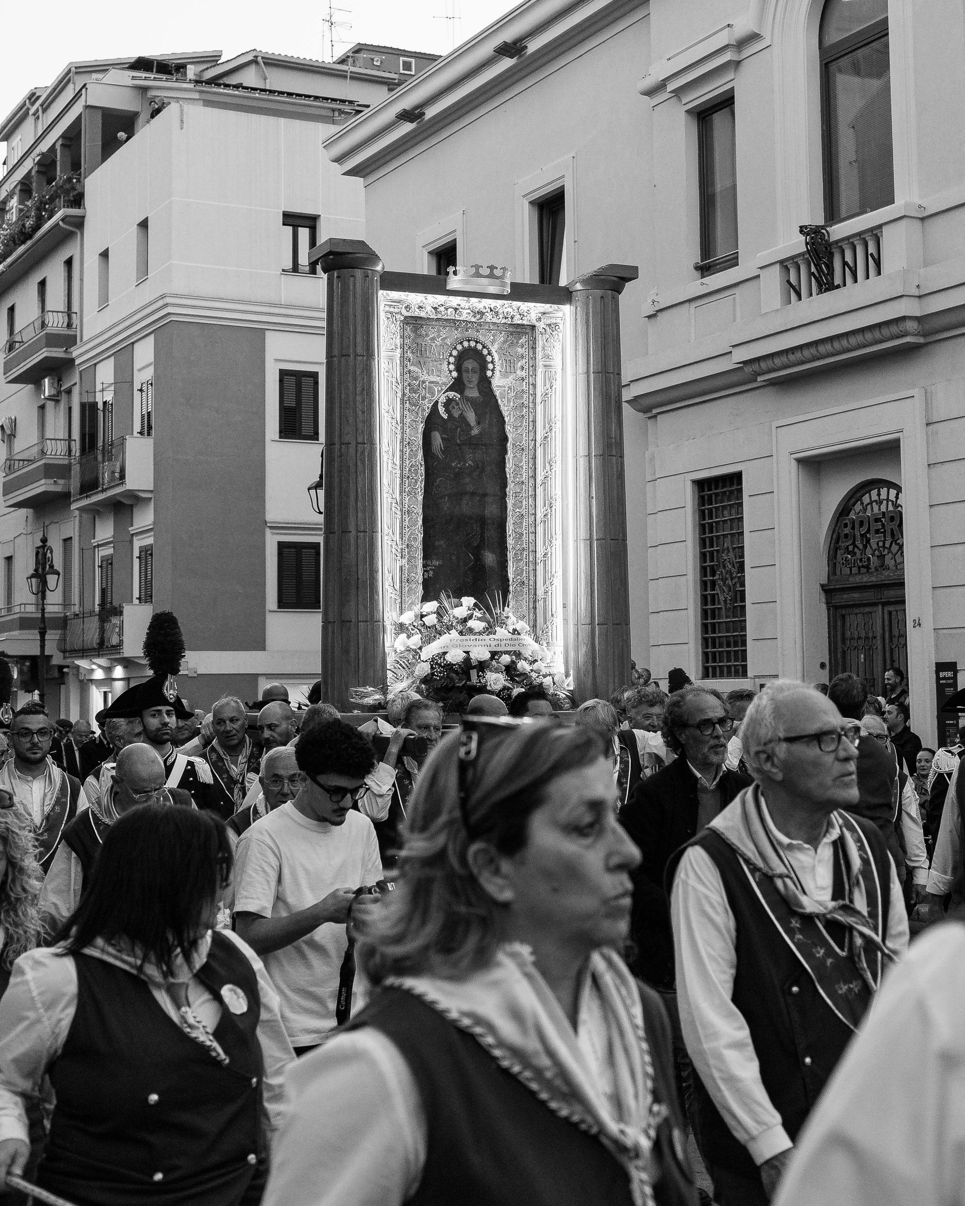 A black and white photo of people walking in front of a building