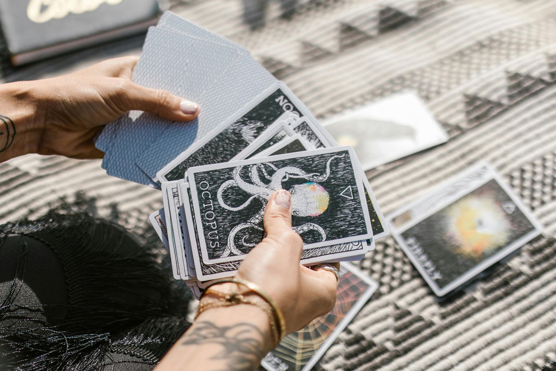 A person is holding a stack of tarot cards in their hands.