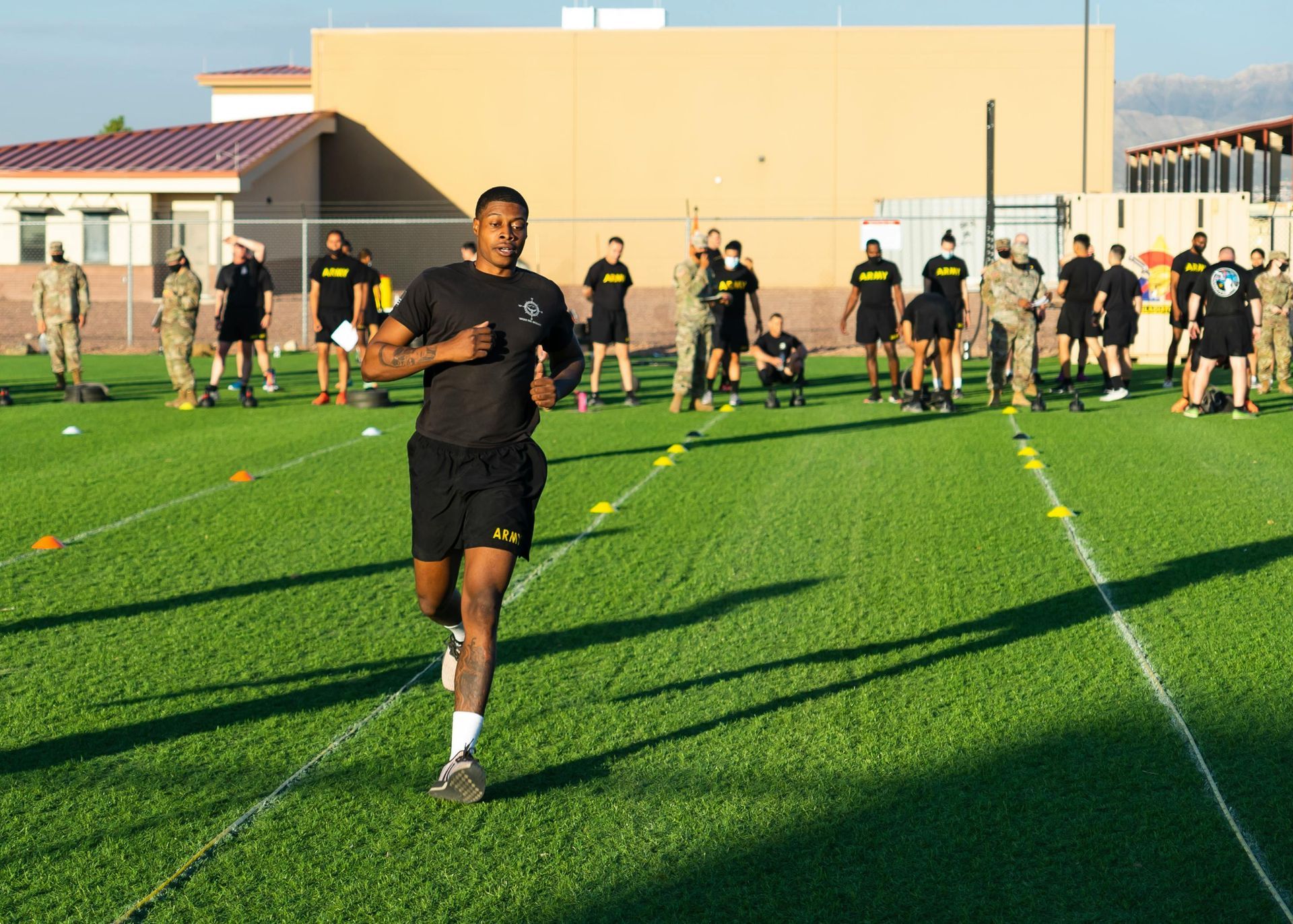 A man running on a field with a group of soldiers in the background