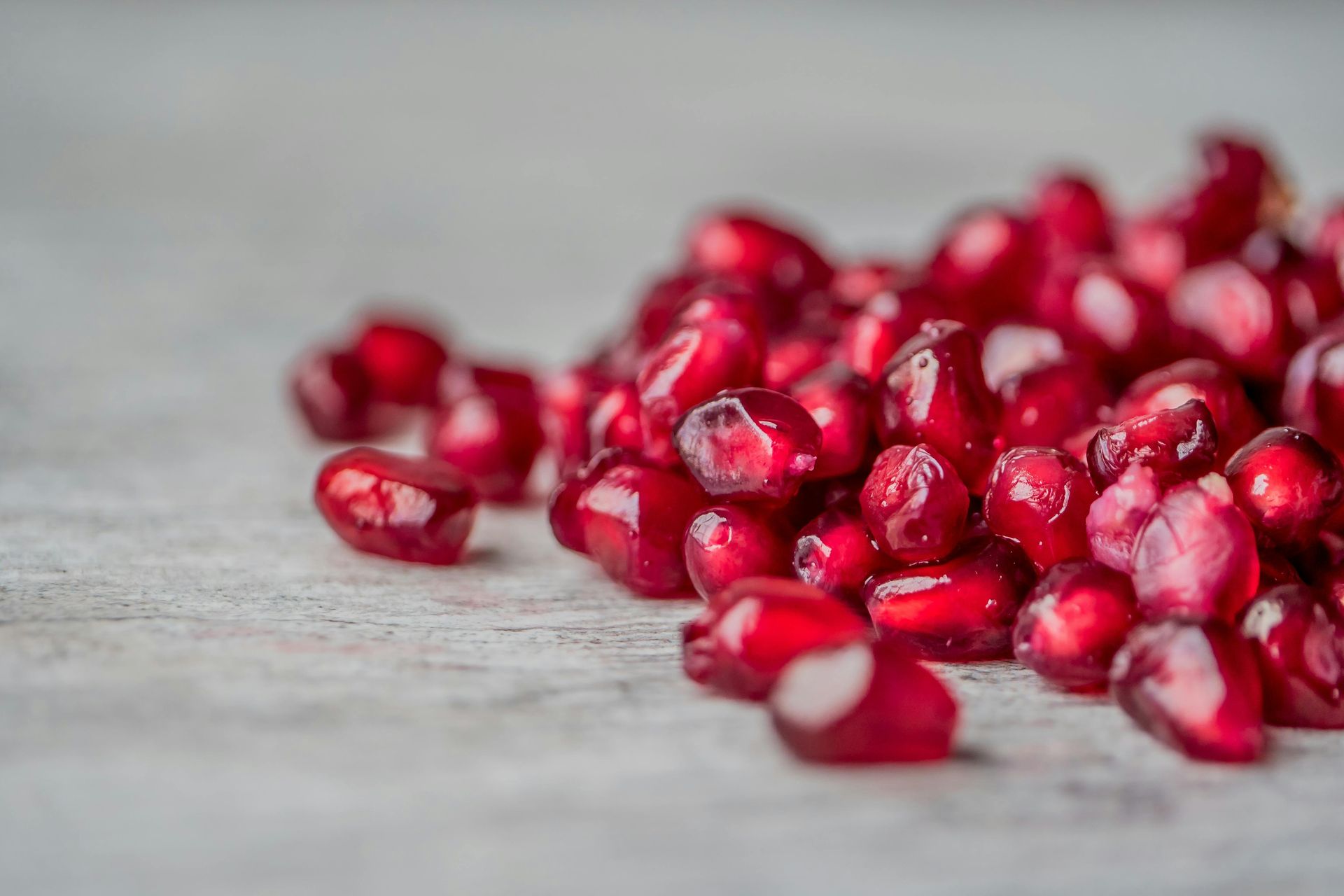 A pile of pomegranate seeds on a wooden table.