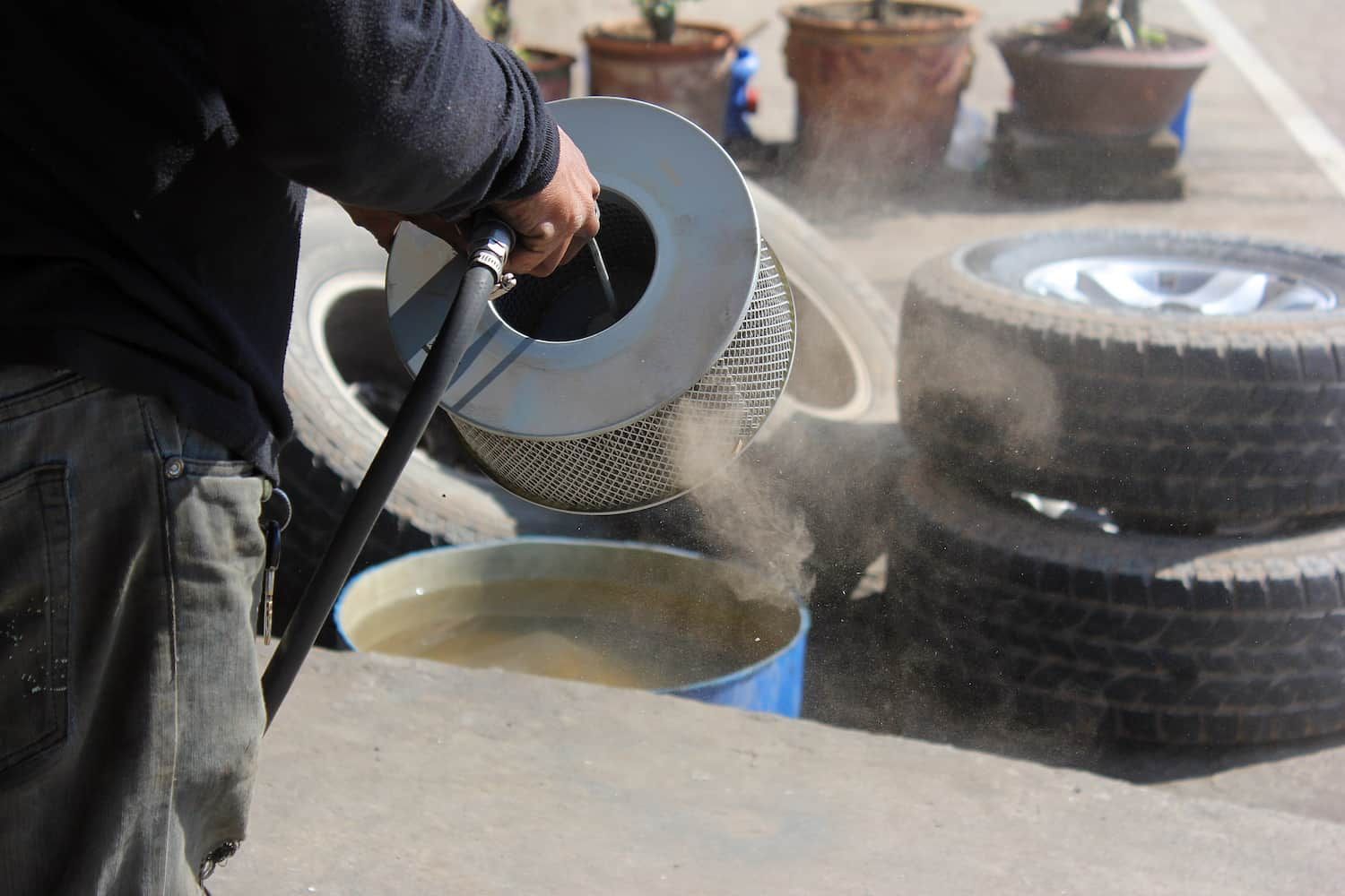 A Man is Pouring Water From a Hose Into a Bucket — FNQ Filters & Parts In Mareeba, QLD