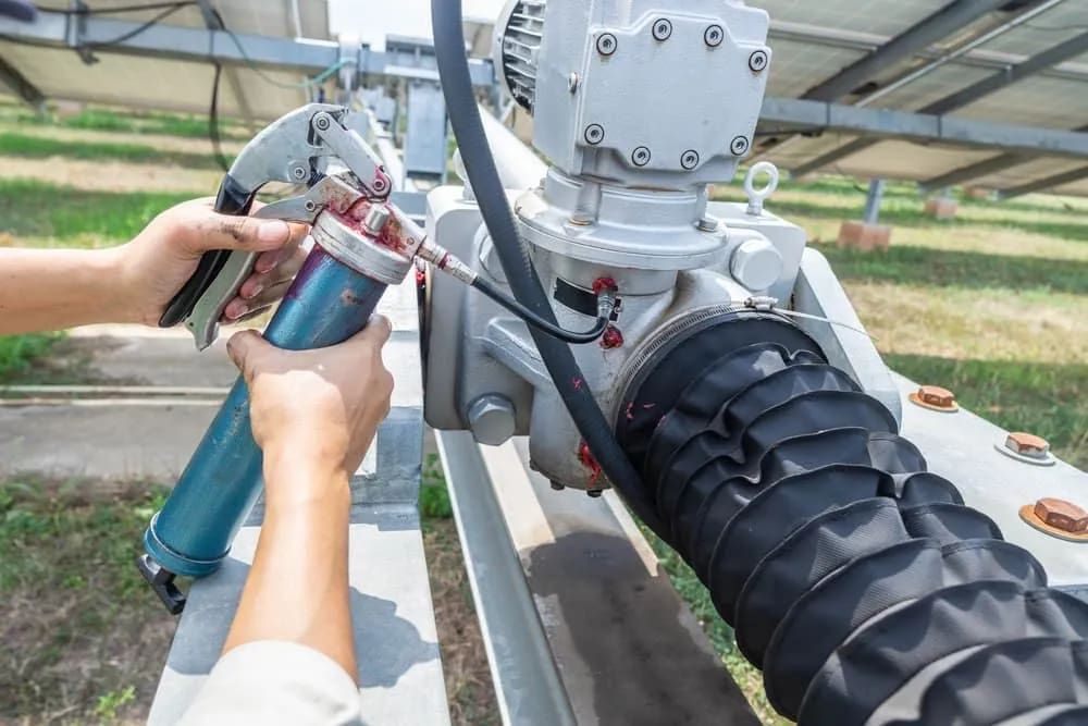 Person Greasing a Solar Panel Component With a Grease Gun Outdoors — FNQ Filters & Parts In Mareeba, QLD