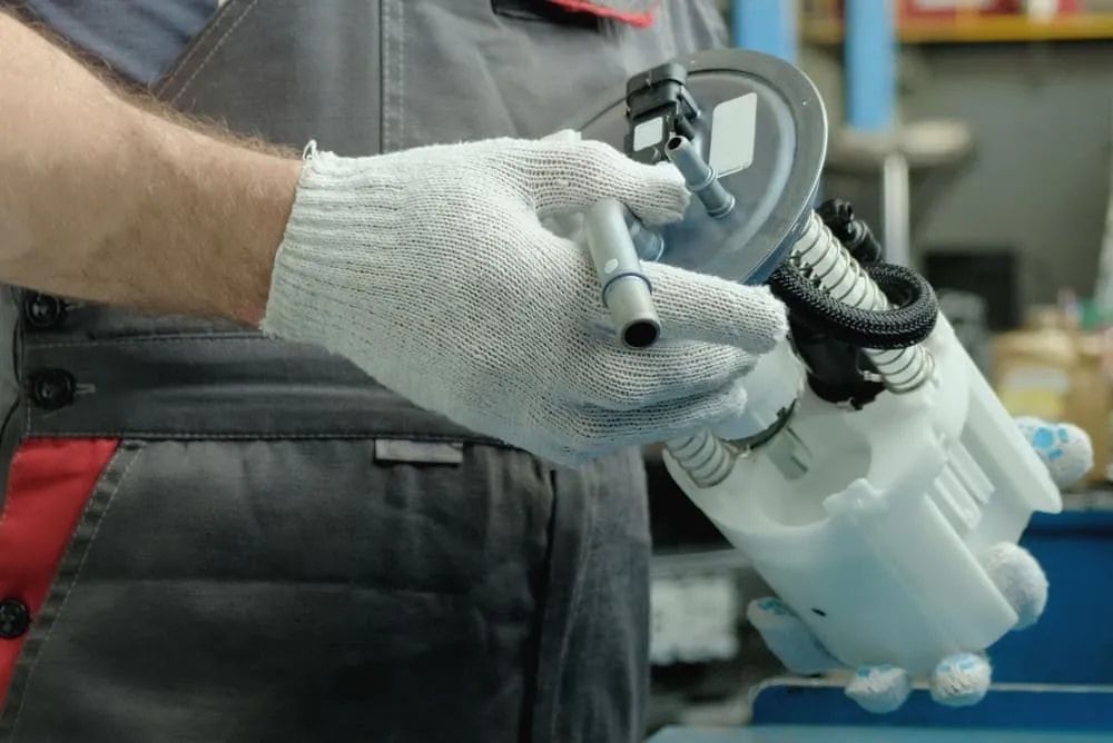 Mechanic's Gloved Hands Holding a Fuel Pump in a Garage Setting — FNQ Filters & Parts In Mareeba, QLD