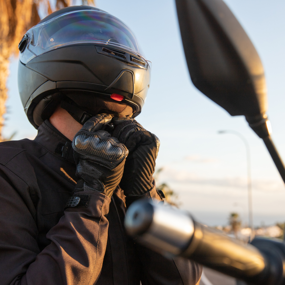 A man wearing a helmet and gloves is sitting on a motorcycle