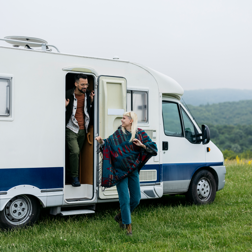 A man and a woman are standing in front of a camper van.