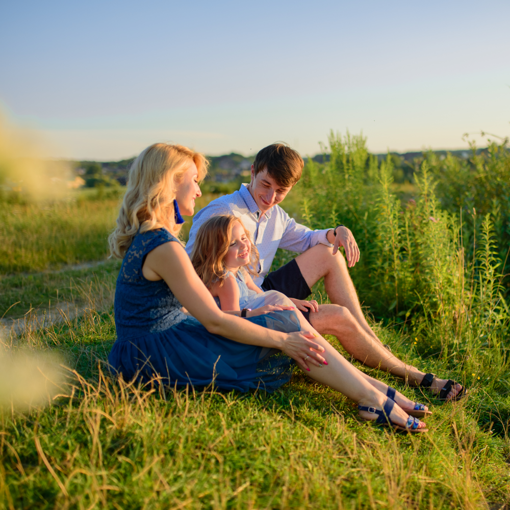 A family is sitting on the grass in a field.