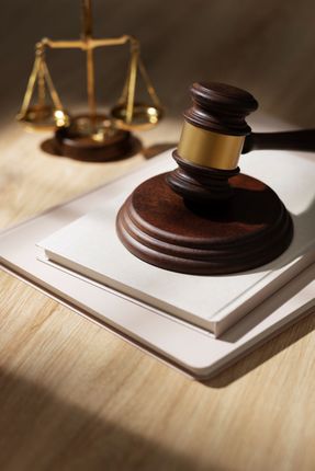 A wooden judge 's gavel is sitting on top of a stack of books.