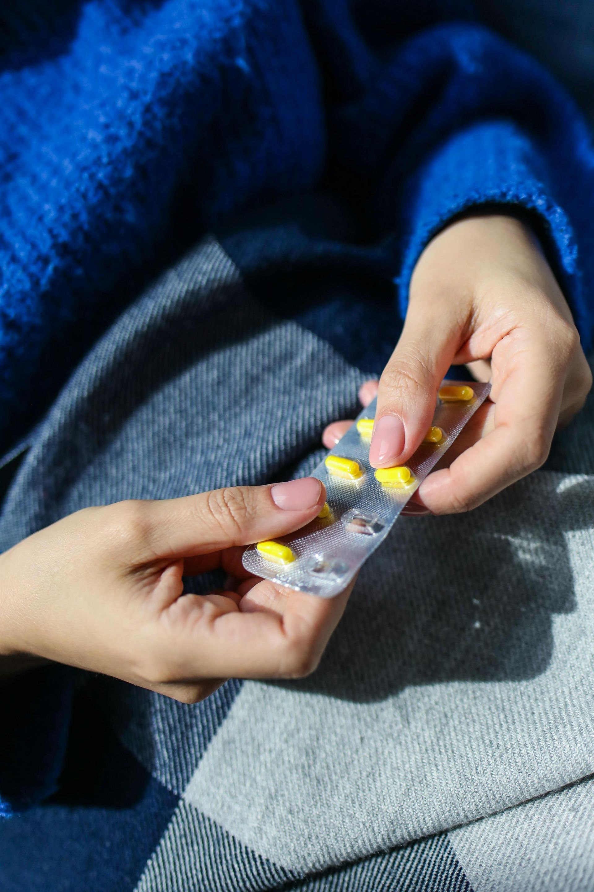 A person is holding a blister pack of pills in their hands.