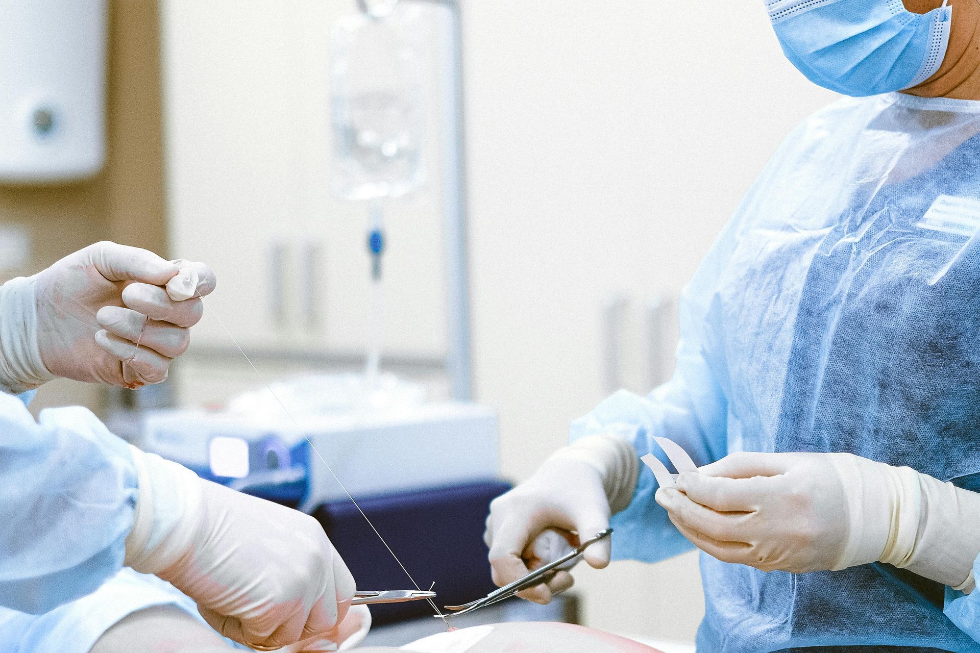 A surgeon is holding a pair of scissors in an operating room.