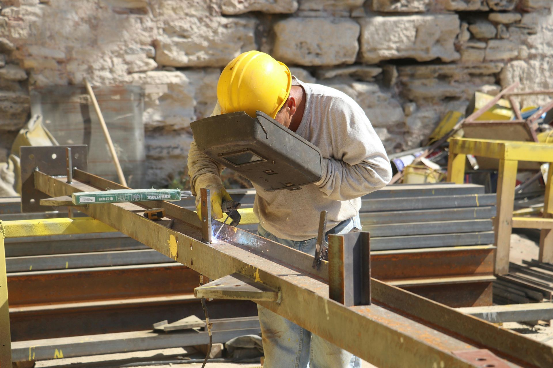 A man wearing a hard hat is welding a piece of metal.