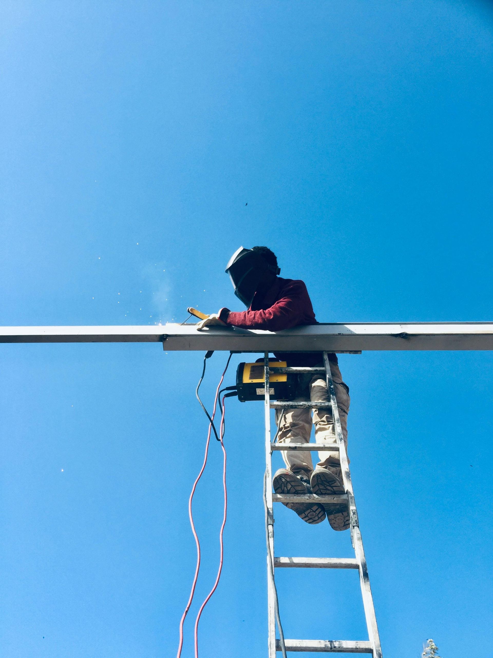 A man is standing on a ladder working on a pipe